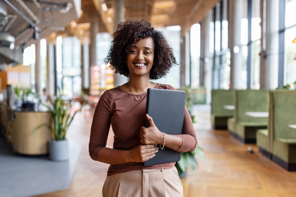 Confident professional woman holding a tablet in a modern office environment.