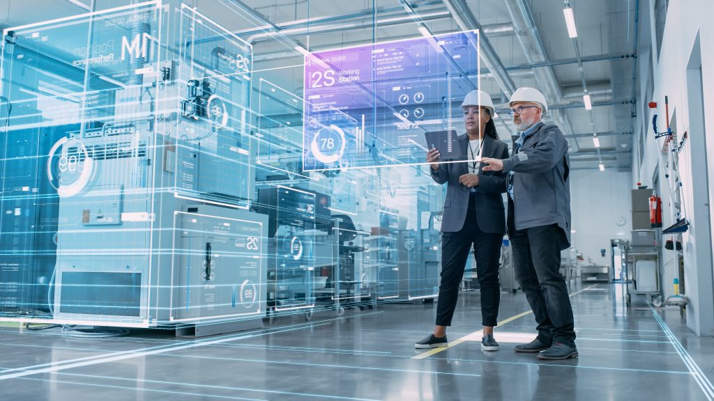 Two engineers, one male and one female, discussing data projections on a digital screen in an industrial setting.